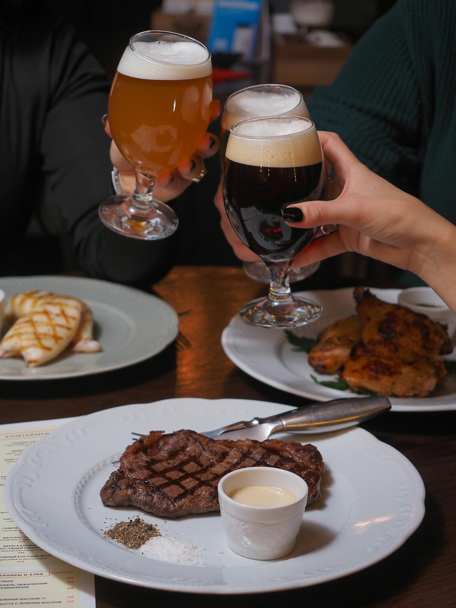 Close-up of gourmet steaks paired with craft beers in a restaurant setting.
